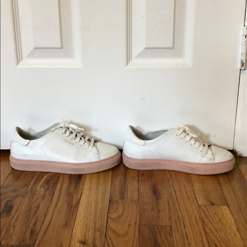 White Axel Arigato sneakers with pink soles.
